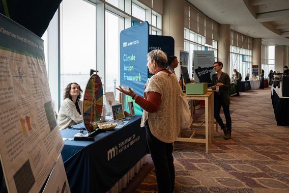 A conference attendees talks with staff of the Minnesota Department of Natural Resources at an info table. 
